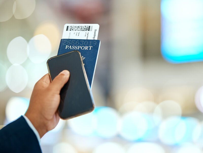 Airport, passport and ticket in hand with phone for online booking, travel and immigration registra.